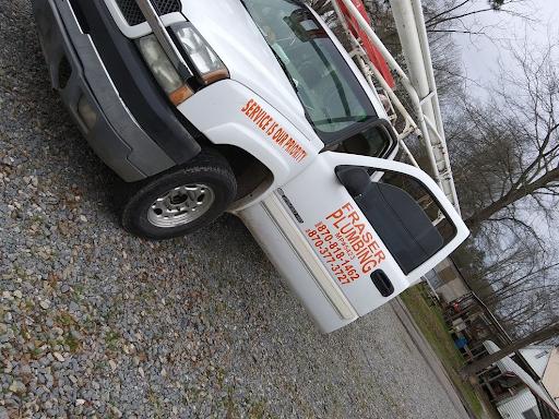 A white service truck with the Fraser Plumbing logo on its driver's door parked in a gravel yard